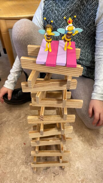 Groepsspelen Kapla! 

De Kapla staat al het hele schooljaar zielig in een hoekje en niemand kijkt er naar om. 😔 Tijd voor een boost! 
We zaten met z’n allen gezellig op de grond in de kring. Ik spreidde de Kapla voor de kinderen uit en we gingen, ieder voor zich, aan het bouwen. Ik ook. Sommige kinderen keken om zich heen en deden anderen na. Andere kinderen hadden zelf fantastische ideeën, zoals hun naam leggen. Ook ik werd geïnspireerd door een kleuter naast me. 
Na enige tijd stopten we met spelen en vertelden elkaar over ons bouwwerk. De kinderen mochten kiezen: verder bouwen of opnieuw beginnen en iets anders proberen. Ik probeerde natuurlijk uit wat ik bij die kleuter had gezien! Dit deden we weer een ronde lang. 

Daarna, in de derde ronde, voegde ik speelfiguren van insecten toe en kreeg het spel een nieuwe impuls. 🐝

Een kleuter verzuchtte: ‘Ik wist niet dat de Kapla zo leuk was!’ 🫶🏼

Na de kring speelde een deel van de kinderen verder en ontstond een waar Kapla paradijs, waar we nog allerlei speelgoed bij haalden. Er vloog zelfs een vlinder rond, met een draad aan de lamp vastgemaakt. 😅 Zoveel enthousiasme! 🤩 Het werd een top Kapla dag met zoveel ruimte voor spel, fantasie en creativiteit! ❤️